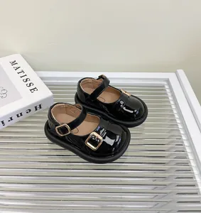 Vista de detalle de zapatos Mary Jane para bebé en charol negro con hebillas doradas