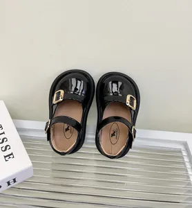 Vista superior de zapatos de charol negro para bebé con elegantes hebillas doradas