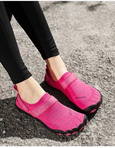 Detailed view of bright pink barefoot water shoes for women worn on asphalt ground
