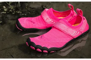 Bright pink quick-dry water shoes with mesh upper and durable rubber sole in wet setting