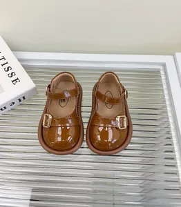 Primer plano de zapatos Mary Jane para bebé en charol marrón con hebilla de dorado