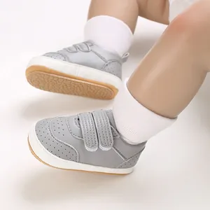 Nahaufnahme von grauen Baby-Lauflernschuhen mit Klettverschluss und weißen Socken