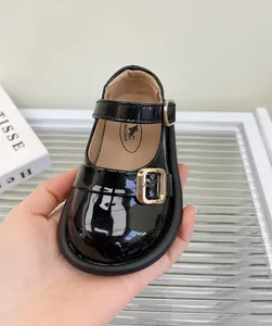 Primer plano de zapato de charol negro para niña con una elegante hebilla dorada