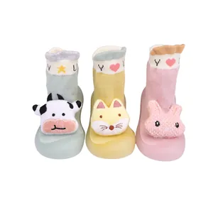 Nahaufnahme von drei Paaren süßer Cartoon Baby Socken Schuhe in Grün Gelb und Rosa Farben