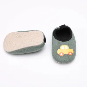 Chaussures de marche pour bébé en velours gris avec écusson de voiture jaune et semelle souple.