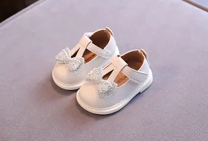Detailansicht der weißen Baby-Prinzessin-Schuhe mit funkelnder Strass-Schleife