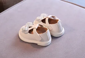 Detail von cremefarbenen Baby-Prinzessin-Schuhen mit Strassschleife.