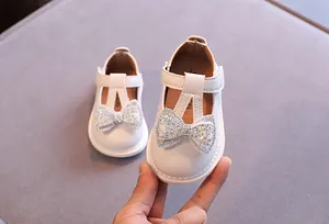 Detailansicht weißer Prinzessinnenschuhe für Kleinkinder mit funkelnder Strass-Schleife