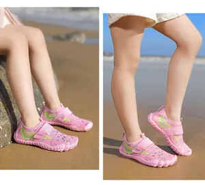 Detailed side view of pink children's water shoes on a sunny sandy beach setting