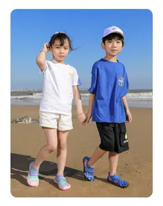 Happy young boy and girl wearing colorful quick-dry water shoes on a sunny sandy beach