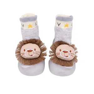 Detailansicht von Babysocken-Schuhen mit einem süßen Plüschlöwen auf grauem Stoff