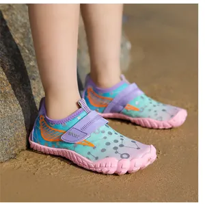 Close-up of colorful gradient children's water shoes on the beach sand