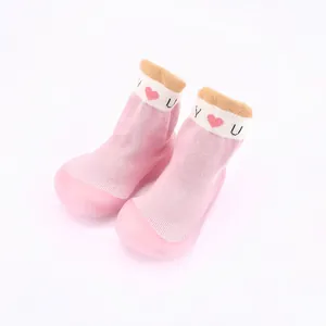 Nahaufnahme von rosa gestrickten Baby-Lauflernschuhen mit weichen Sohlen und Herzmuster