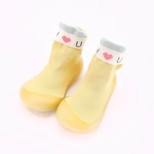 Detailaufnahme gelber Strick-Babyschuhe mit rotem Herz-Design am oberen Bund.