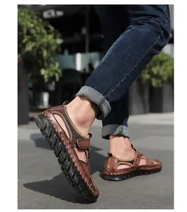 Vista lateral de sandalias de cuero marrón cosidas a mano para hombre con jeans azules