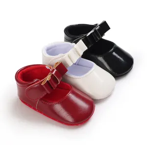 Detailed view of red, white, and black shiny leather baby girl Mary Jane shoes with bows