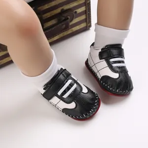 Dettaglio di scarpe primi passi neonato bianco e nero con suola in gomma rossa antiscivolo
