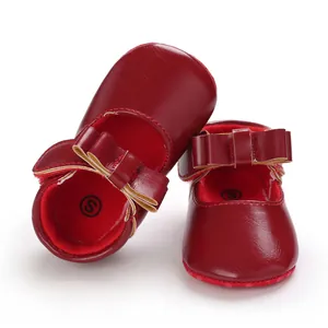 Detail shot of red baby princess walking shoes with elegant bow decorations and soft leather.