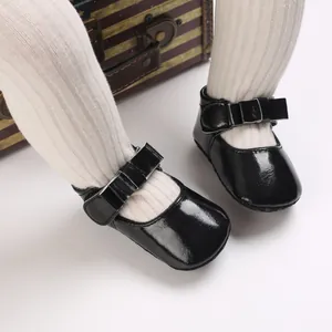 Close-up of elegant black patent leather baby princess shoes with a stylish bow detail