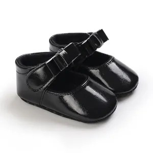 Detail view of shiny black patent leather baby girl Mary Jane shoes featuring a bow.