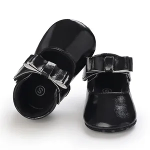 Detailed view of black patent leather baby walker shoes with decorative bow.