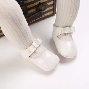 Close-up view of white baby girl princess shoes with decorative bow and soft sole detail