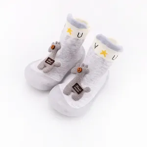 Detailed view of gray cartoon baby walker shoes with soft rubber soles and giraffe doll.