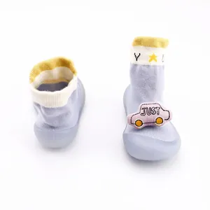 Detail showing cute light blue baby sock shoes featuring a pink cartoon car plush toy decor