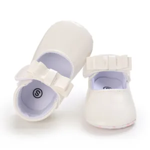 Close-up of cream baby girl walking shoes featuring a bow and soft leather texture