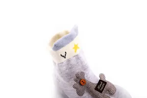 Detail view of children's knit sock shoe featuring a cute handmade cartoon doll accessory.