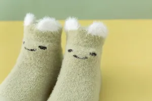 Nahaufnahme der weichen Plüschstruktur und der süßen 3D-Ohren der grünen Babysocken.