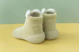 Nahaufnahme der flauschigen hellgrünen Babyhausschuhe mit süßen Bärenohren und weichen Sohlen.