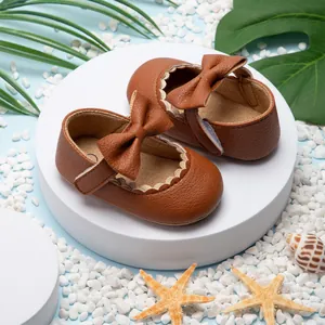 Detailopname van bruine baby Mary Jane schoentjes met strikken op een zomerse strandachtergrond