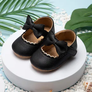 Gedetailleerd overzicht van zwarte leren babyschoenen met een grote strik en schulprand