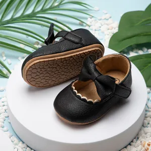 Detailopname van zwarte baby prinsessenschoenen met strik en antislip rubberen zooltextuur