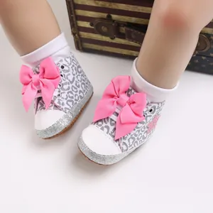 Primer plano detallado de zapatos de bebé con estampado de leopardo y lazos rosas
