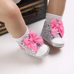 Detalle de zapatos de bebé con estampado de leopardo y gran lazo rosa para niñas