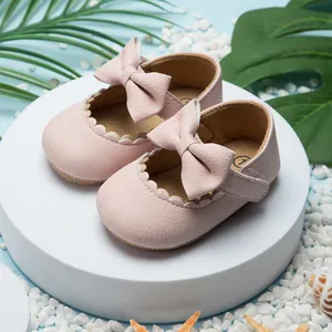 Close-up detail van roze baby prinsessenschoenen met strikken en schulpranden op blauwe basis.