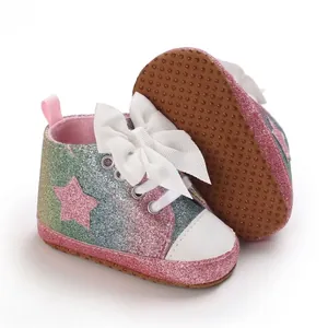 Detalle de zapatos de gateo con purpurina para niña con gran lazo blanco y estrella