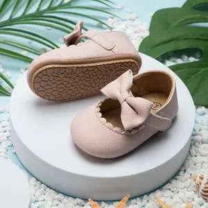 Detailopname van roze babyloopschoentjes met een strik en antislip rubberen zool