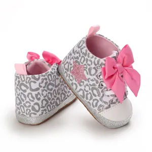Vista detallada de zapatos de bebé niña con estampado de leopardo y gran lazo rosa brillante.