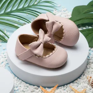 Detailopname van roze baby prinsessenschoentjes met grote strik en geschulpte randen.
