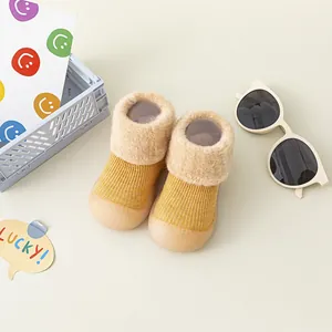 Nahaufnahme von warmen gelben Strick-Babysöckchen mit Plüschkragen und weicher Gummisohle.