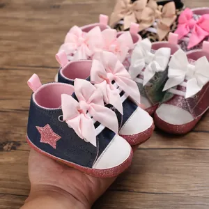 Primer plano de lindos zapatos para bebé niña azul marino con lazo rosa y suela de purpurina