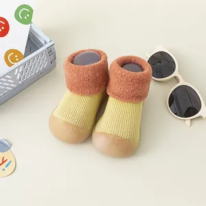 Nahaufnahme von gelben Strick-Babyschuhen mit orangefarbenen Manschetten und weichen Sohlen.