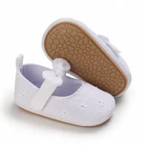 Vista macro de zapatos de princesa para bebé blancos con bordado floral y suela blanda