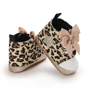 Detalle de zapatos de bebé con estampado de leopardo, lazo rosa y suela con purpurina.