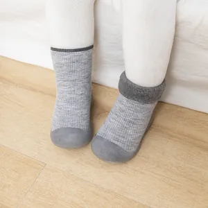 Nahaufnahme von warmen grauen Strick-Babysocken-Schuhen mit weicher Gummisohle
