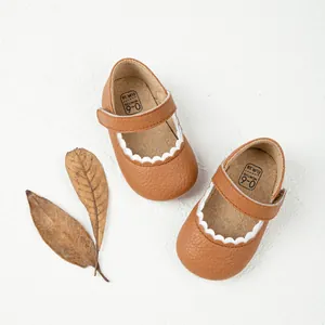Detail van bruine lederen baby Mary Janes met witte geschulpte randen en gedroogde bladeren