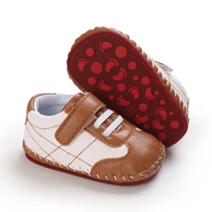 Dettaglio scarpe primi passi neonato marrone e bianco con suola rossa antiscivolo